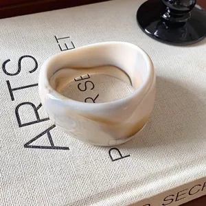 Dettaglio ravvicinato di un bracciale in resina marmorizzata con venature beige e marroni