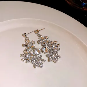 Detail view of vintage crystal flower drop earrings with hollow petals on white plate