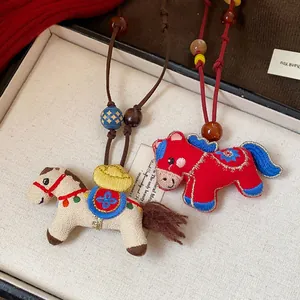 Detailed close-up showing the handcrafted embroidery and wooden beads on horse pendants.