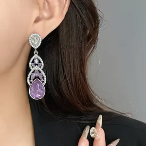 Detail shot of elegant purple teardrop earrings with silver needles and rhinestones