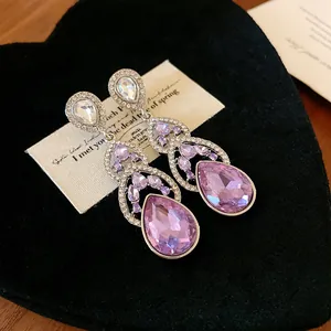 Close-up detail of elegant purple teardrop crystal dangle earrings with silver finish