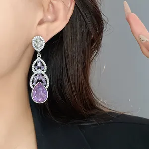 Detailed view of elegant long silver needle earrings featuring purple water drop crystals
