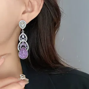 Detailed macro view of elegant silver drop earrings featuring teardrop purple crystals