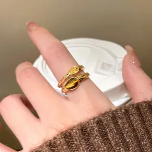 Close-up view of 18k gold plated rings with tiger eye and zircon stones on a finger.