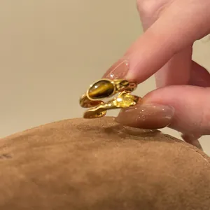 Close-up of 18k gold plated open ring featuring tiger eye stone and yellow zircon details.