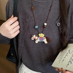 Close-up detail of a handmade embroidered horse pendant necklace with rustic wooden beads