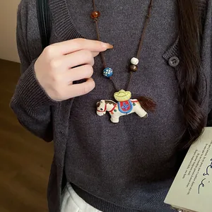 Detailed view of a vintage-style embroidered horse pendant necklace with wooden beads.