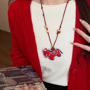 Detailed view of red embroidered horse pendant necklace with rustic wooden and resin beads