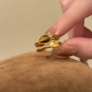 Detail view of 18k gold plated open ring set with tiger eye and yellow zircon stones