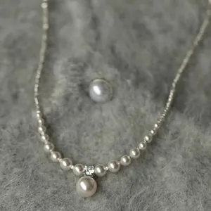 Detailopname van een elegante parelketting met zilveren kralen op zacht grijs imitatiebont.