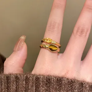 Close-up detail of 18k gold plated open rings featuring yellow zircon and tiger eye stones