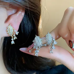 Primo piano di orecchini a foglia con zirconi scintillanti e eleganti gocce di pietra pendenti