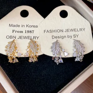 Dettaglio di orecchini a clip a foglia con CZ in finiture oro 18k e argento.