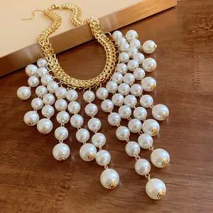 Close-up detail of a French style gold chain necklace with white pearl tassels.