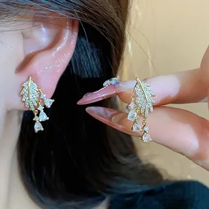 Primo piano di orecchini a foglia placcati oro 18 carats con nappe in zircone.