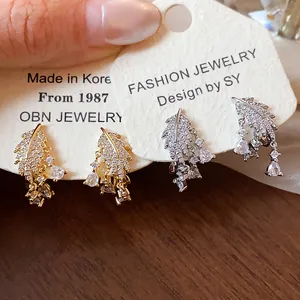 Dettaglio di orecchini a clip a foglia oro e argento con brillanti cristalli zirconi.