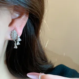 Dettaglio ravvicinato di orecchini a clip a forma di foglia con pietre di zircone brillanti