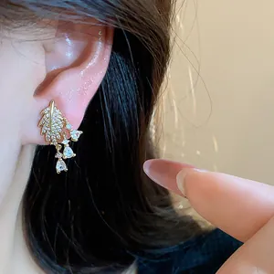 Dettaglio di orecchino a clip a foglia con zirconi scintillanti e placcatura in oro