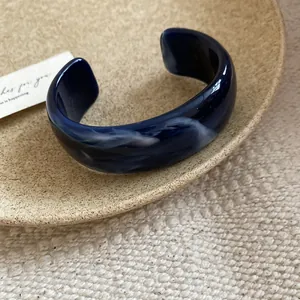 Elegante brazalete de acrílico jaspeado azul con patrones de remolinos blancos únicos