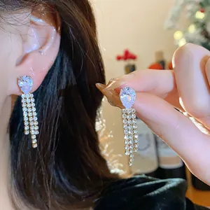 Detail of elegant teardrop earrings with sparkling rhinestone tassels worn by a model