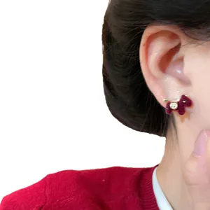 Elegant red flocked pony stud earrings with silver needle shown on female model ear