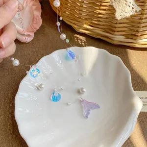 Close-up of iridescent mermaid tail and shell charms on an elegant pearl necklace