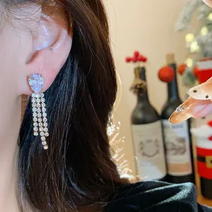 Close-up of elegant water drop tassel earrings with glittering crystals on model's ear