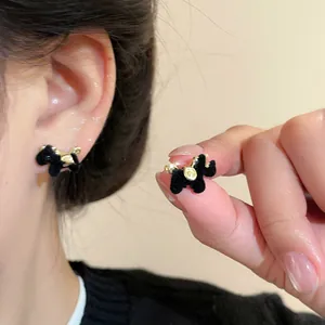 Detail shot of black flocked horse stud earrings worn on ear and held by hand