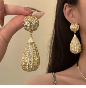 Eleganti orecchini a goccia pavé color oro con strass scintillanti in vista dettagliata.