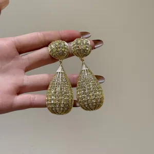 Vista dettagliata di grandi orecchini a goccia dorati con pavé di strass brillanti ed eleganti