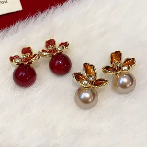 Primer plano de elegantes pendientes de perlas con flores vintage rojo y oro champán