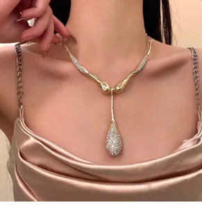 Primo piano di una collana dorata irregolare con pendente a goccia in strass brillanti