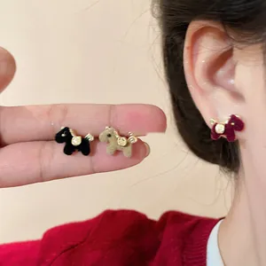 Flocked horse stud earrings shown on fingers and ear for scale, style and texture