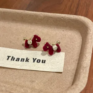 Close-up of red flocked horse stud earrings with gold accents and sparkling crystals