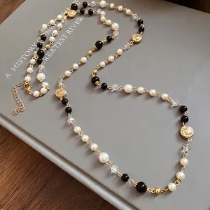 Vintage long pearl necklace featuring rose charms and elegant black beads on a grey background.