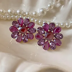 Elegantes pendientes de flor de cristal púrpura estilo vintage en una bandeja de perlas