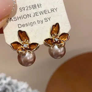 Primer plano de pendientes de flores de esmalte vintage con perlas y plata S925.