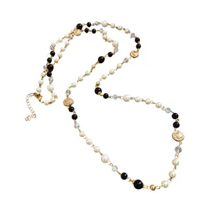 Elegant long necklace with white pearls, black beads, and gold floral accents in retro style.