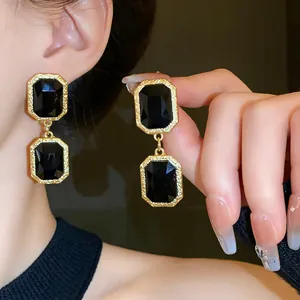 Close-up of vintage geometric black crystal earrings with textured gold frame and luxury finish