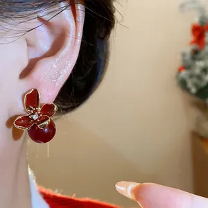 Primer plano de pendientes de flor roja con gota de aceite, perla y cristal