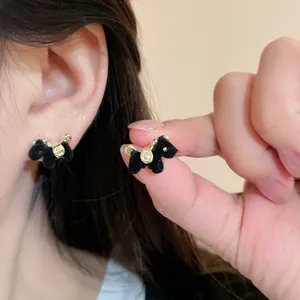 Detailed close-up of black flocked horse stud earrings with gold hardware accents