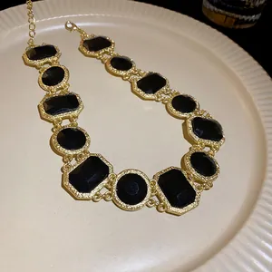 Vintage gold chain necklace with black geometric crystal stones in a macro detail view
