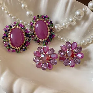 Primer plano de pendientes vintage ovalados y broches de cristal de flores sobre una concha