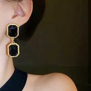 Detail view of vintage gold earrings featuring double-layered rectangular black crystals on model