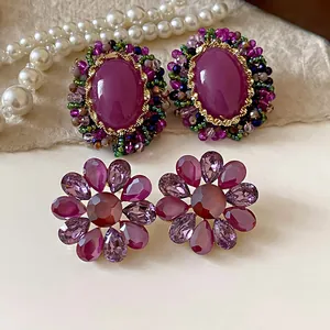 Primer plano de pendientes vintage de cristal púrpura ovalados y con forma de flor