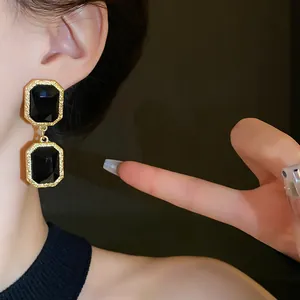Close-up shot of vintage geometric drop earrings with black gemstones in gold frames