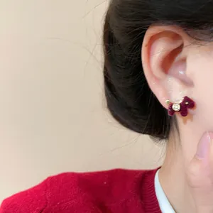 Close-up view of burgundy flocked horse stud earrings featuring a gold smiley face