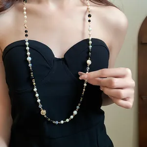 Close-up of a long vintage necklace featuring white pearls and gold floral coins