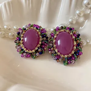 Primer plano de pendientes vintage de cristal púrpura con corona de cuentas de colores