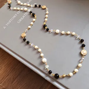 Detailed close-up of a vintage long pearl necklace featuring black beads and gold floral charms